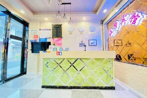 A hotel reception area with a reception desk, a digital screen, and a neon sign. - Yuanmeng Hotel (Shanghai)