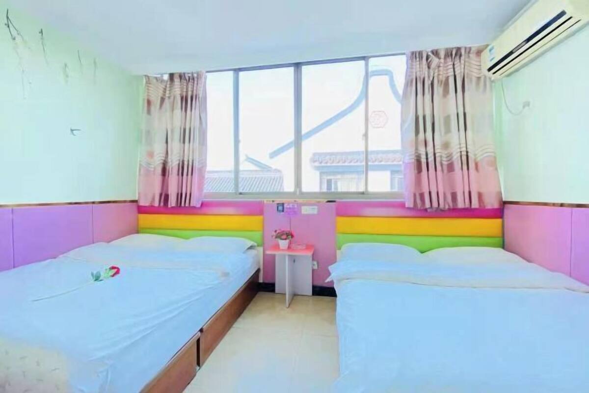 A room with two beds, a small table, and a window with curtains.