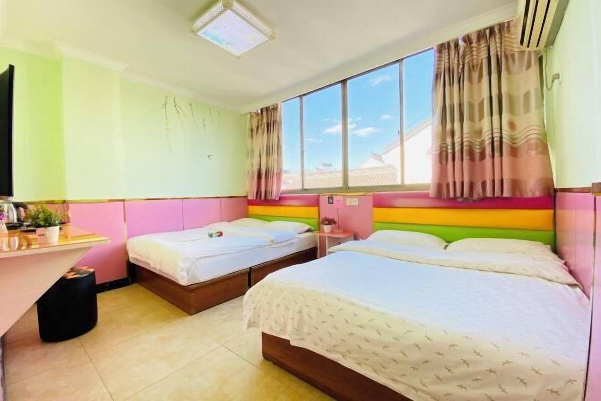 A room with two beds, a desk, and a window with curtains.