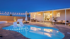 A swimming pool with lounge chairs, a dining area, and a covered patio. - Pool, Spa, Pickleball & Piano Near Pioneertown Harmony House by Avantstay (Yucca Valley)