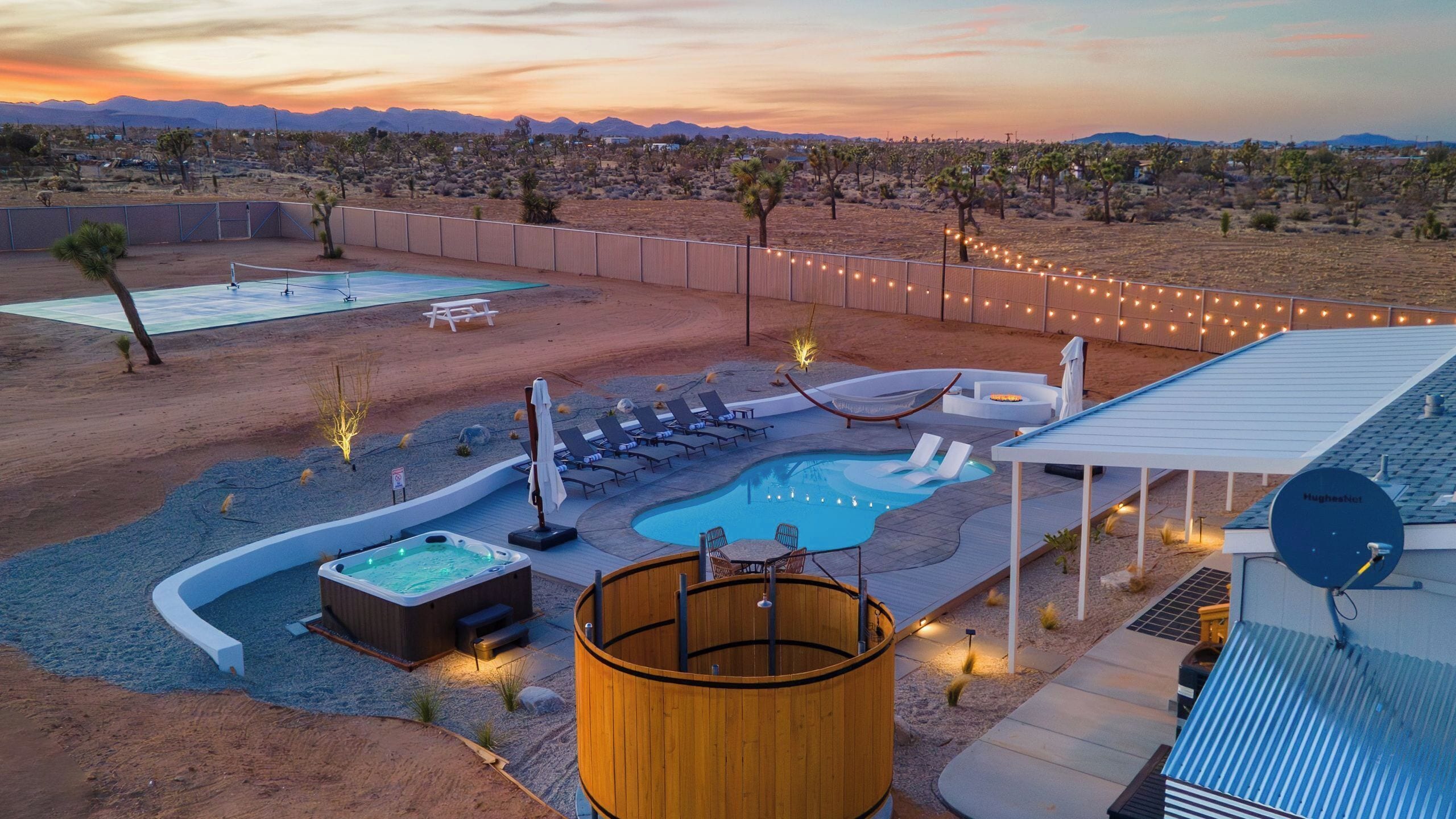 A pool area with hot tubs, lounge chairs, and a wooden barrel.