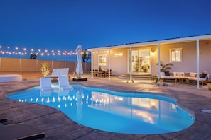 A swimming pool with lounge chairs and a covered patio area. - Pool, Spa, Pickleball & Piano Near Pioneertown Harmony House by Avantstay (Yucca Valley)