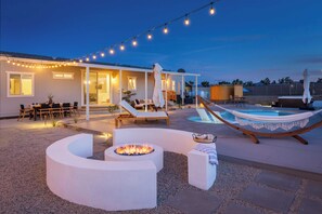 A modern outdoor living area with a pool, lounge chairs, and a fire pit. - Pool, Spa, Pickleball & Piano Near Pioneertown Harmony House by Avantstay (Yucca Valley)