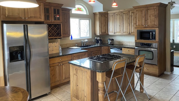 A kitchen with wooden cabinets, stainless steel appliances, a built-in oven, and a bar area with a chair. - 2 story, private, quiet upscale neighborhood MINUTES FROM 4 MAJOR SKI RESORTS (West Jordan)