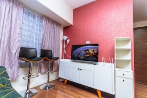 Cozy living space with a flat-screen TV, white cabinet, and comfortable seating for two.
