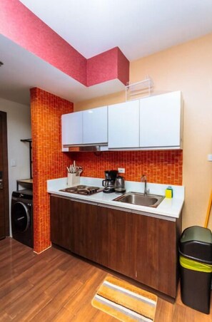 Compact kitchen with a modern design, featuring a sink, coffee maker, and countertop for food preparation.