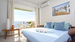 Een hotelkamer met een bed, een tafel en uitzicht op zee.