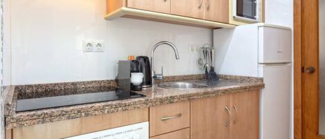 A compact kitchen with a built-in microwave, a stovetop, and a sink.
