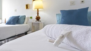 Een hotelkamer met een net opgemaakt bed, een nachtkastje met een lamp en een wand met ingelijste foto's.