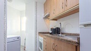 Een compacte keuken met houten kastjes, een granieten aanrechtblad, een ingebouwde oven en een vaatwasser.