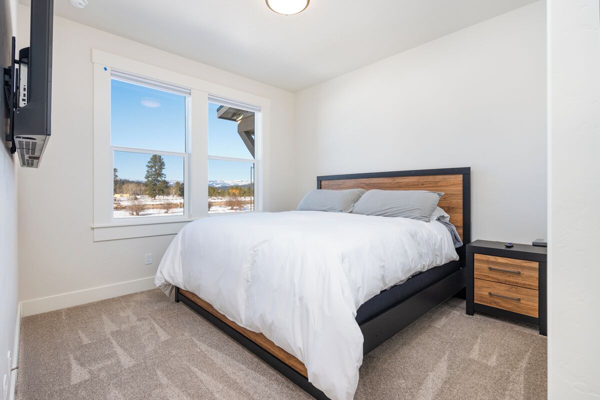 A bedroom with a bed, a nightstand, a window with a view, and a ceiling light.