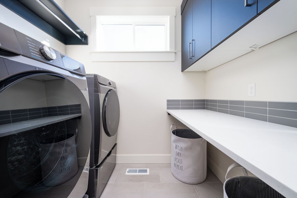 Une buanderie équipée d’un lave-linge, d’un étendoir et d’une poubelle.