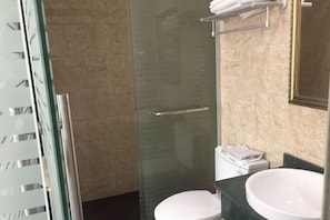 A bathroom with a glass shower enclosure, a white toilet, and a large sink. - Shenzhou Hotel (Shanghai)