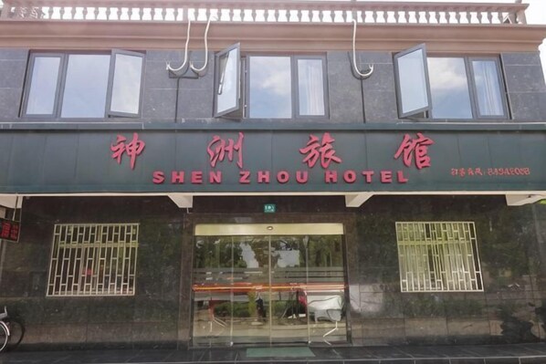 A hotel entrance with a sign in Chinese characters and English text.
