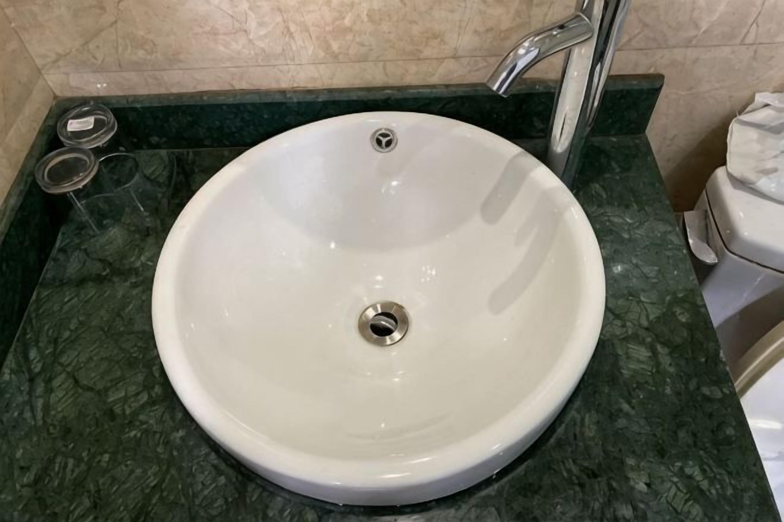 A bathroom with a white sink, a marble countertop, and a toilet.