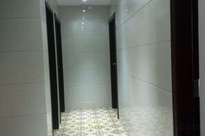 A corridor with tiled walls and floor, leading to a door at the end. - Shenzhou Hotel (Shanghai)