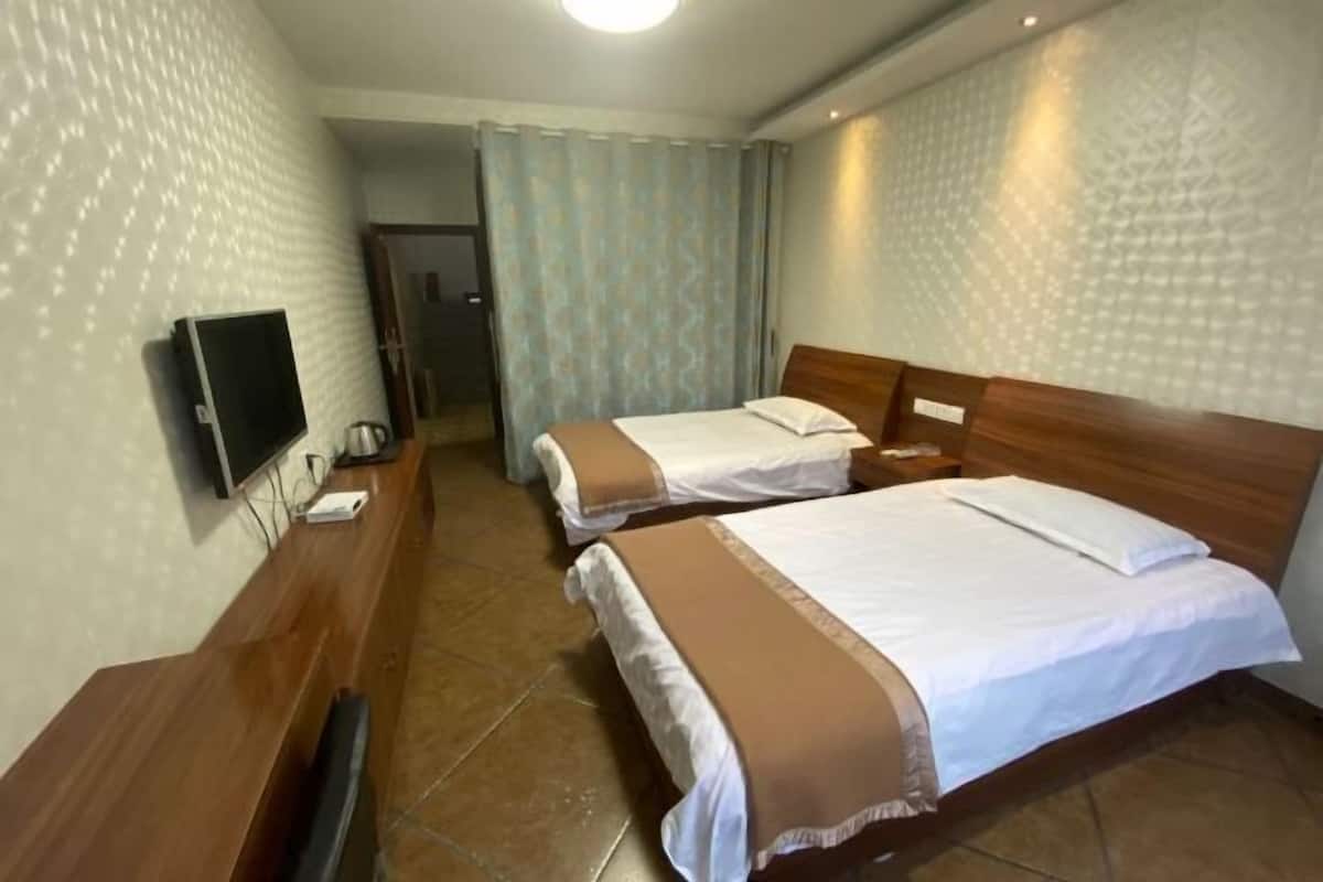 Una habitación de hotel con dos camas, un televisor y un escritorio de madera.