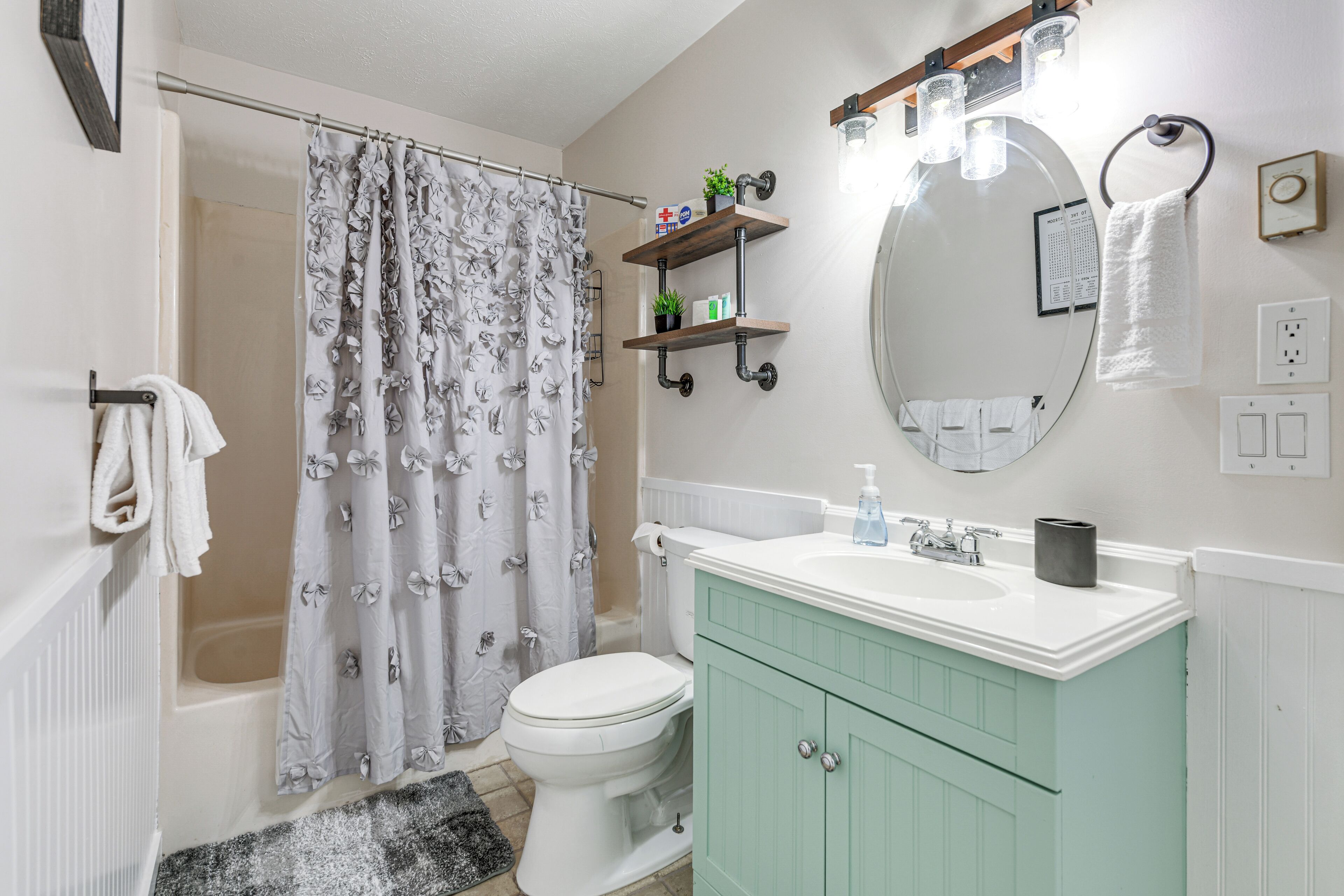 Un baño con cortina de ducha, inodoro, lavabo y espejo.
