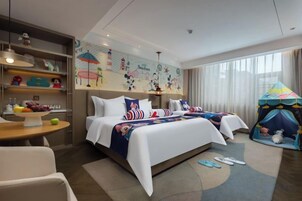 Habitación de hotel con una cama grande, un escritorio, una silla y una pequeña mesa con frutas.
