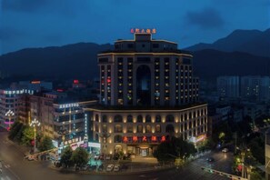 A multi-story hotel with a central courtyard, surrounded by other buildings. - Yelang Hotel (Hezhang)