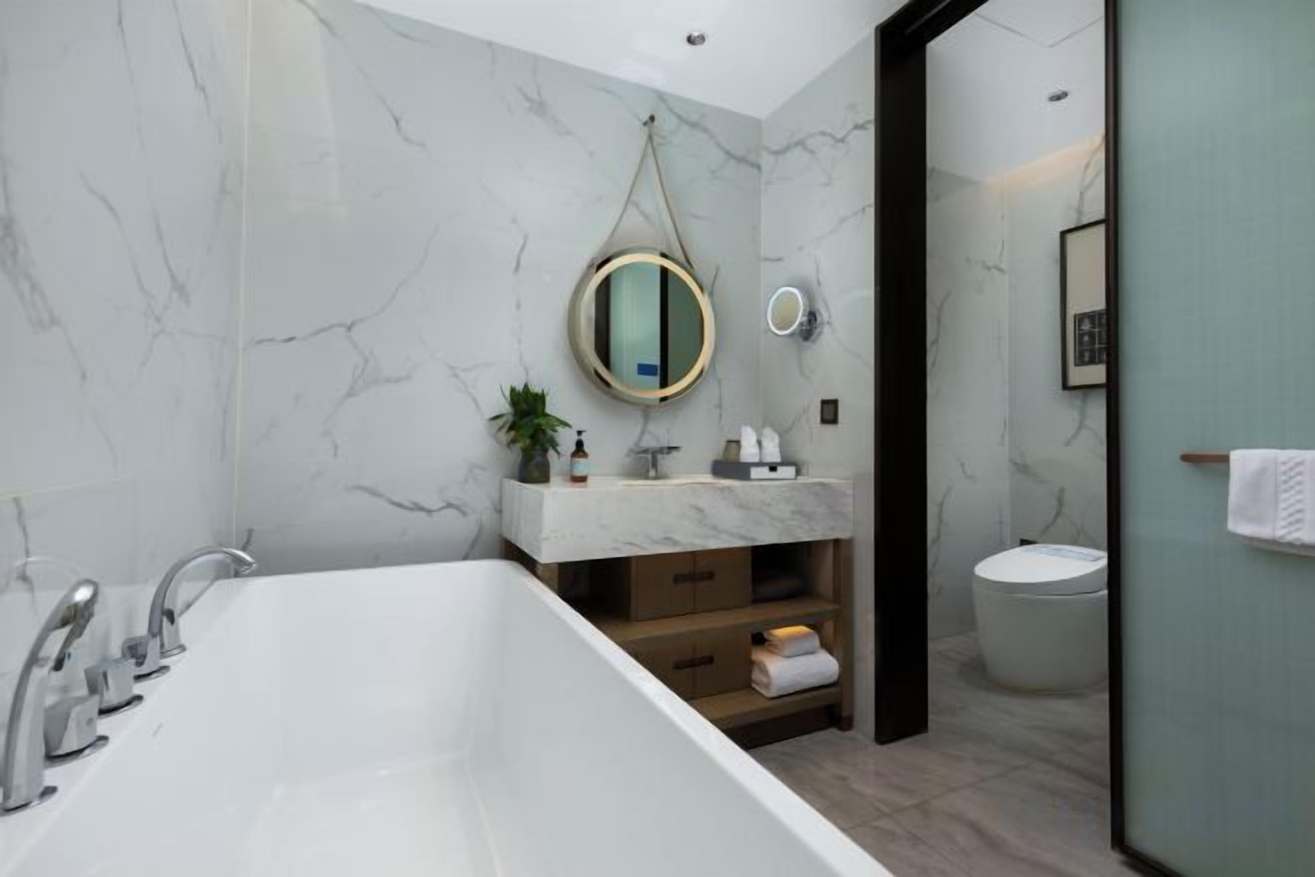 A modern bathroom with a freestanding bathtub, a vanity with a marble countertop, and a toilet.