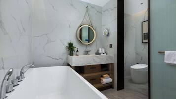 A modern bathroom with a freestanding bathtub, a vanity with a marble countertop, and a toilet.