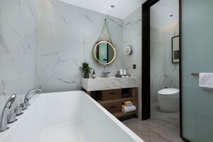 Un baño moderno con una bañera independiente, un lavabo con encimera de mármol y un inodoro.