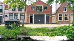 Een rij traditionele bakstenen huizen met een gracht ervoor.