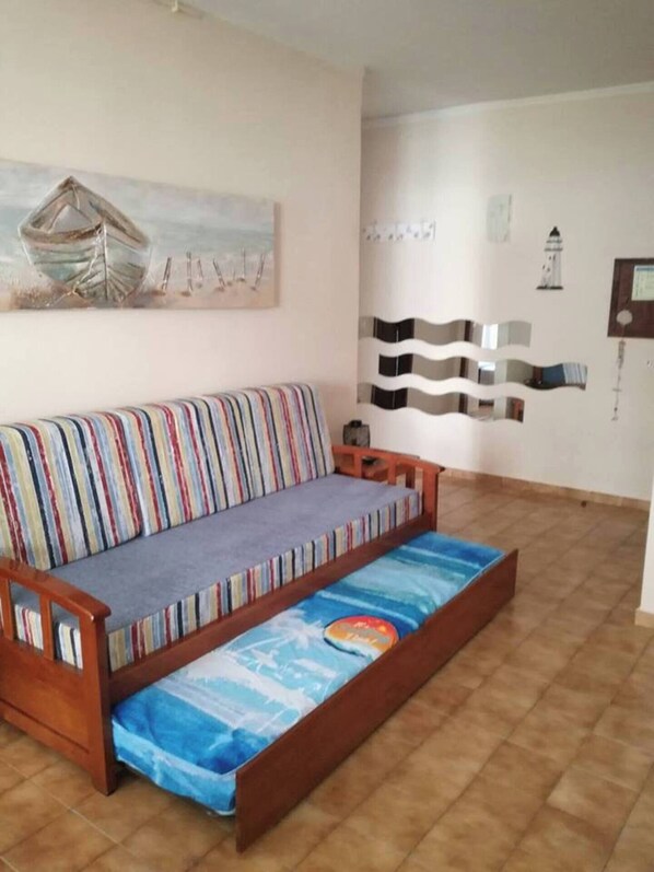 A room with a striped sofa, a small table, and a wall with abstract art and a certificate.