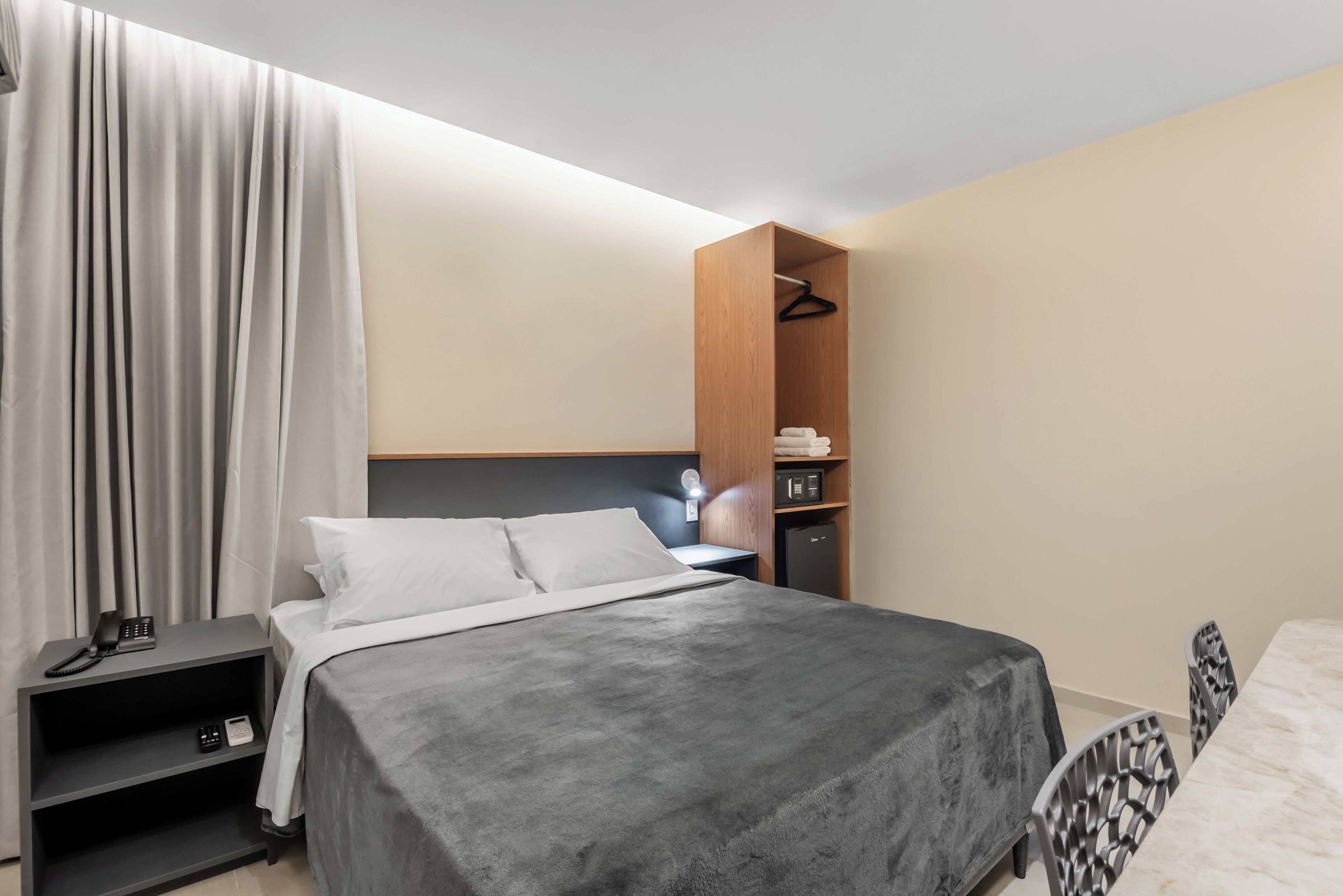 Una habitación de hotel moderna con cama, mesita de noche y armario.