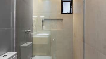 Un baño moderno con ducha envuelta en vidrio, inodoro y lavamanos.
