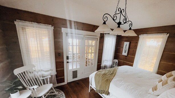 A bedroom with a bed, a rocking chair, a desk, and a window with a view. - Nashville Haven Hideaway- Cozy 3 Bedroom House (Nashville)