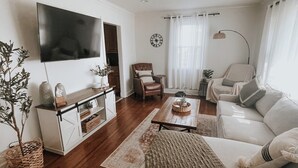 A living room with a flat-screen TV, a sofa, a coffee table, and a chair. - Nashville Haven Hideaway- Cozy 3 Bedroom House (Nashville)