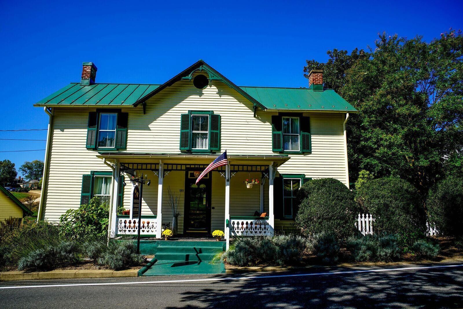 A two-story house with a green roof and a porch.