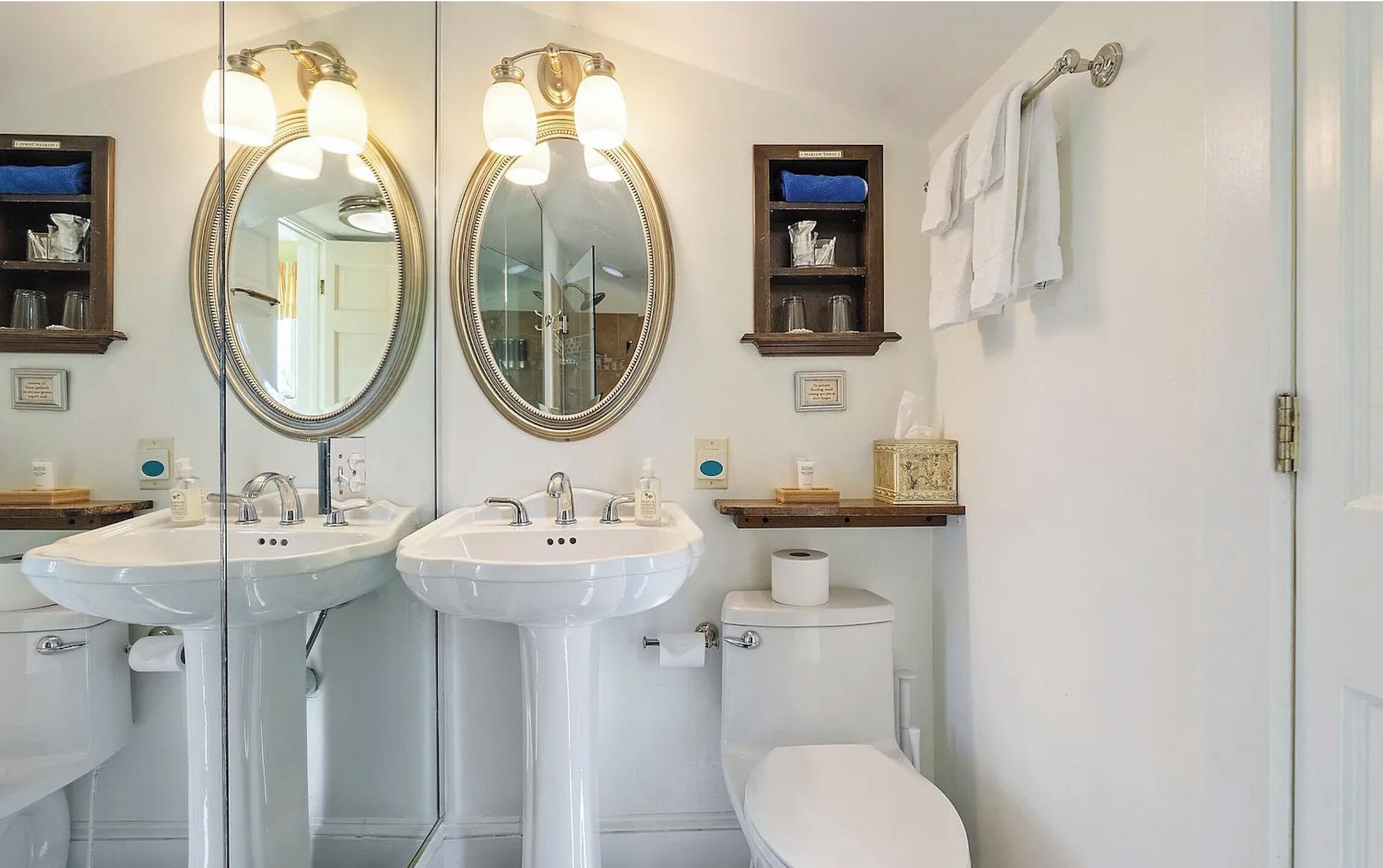 A bathroom with two sinks, a toilet, and a mirror.