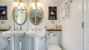 A bathroom with two sinks, a toilet, and a mirror.