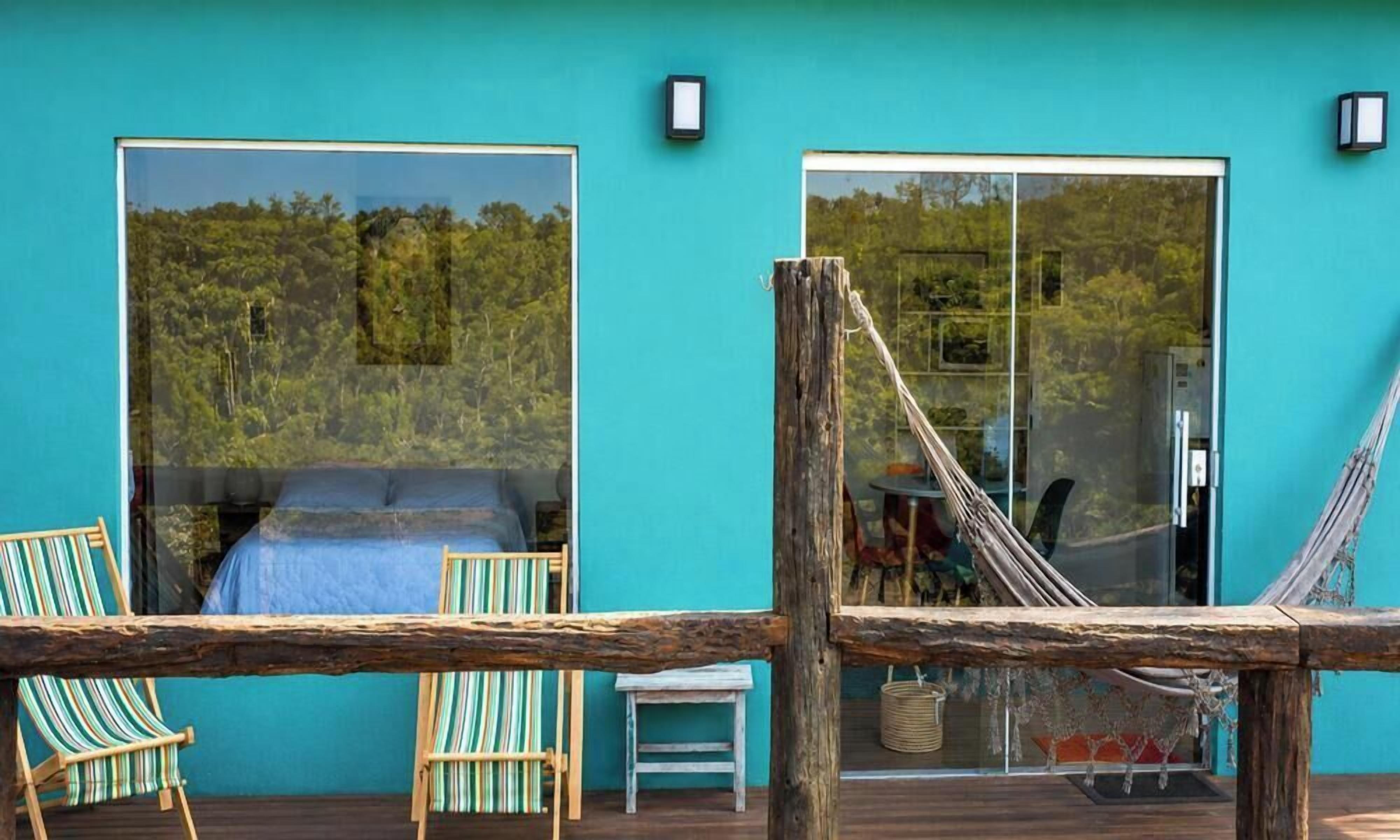 A room with a large window, a hammock, and two striped chairs.