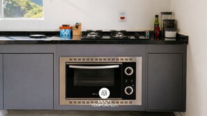 A kitchen with a built-in oven, a gas stove, and a window overlooking a mountainous landscape.