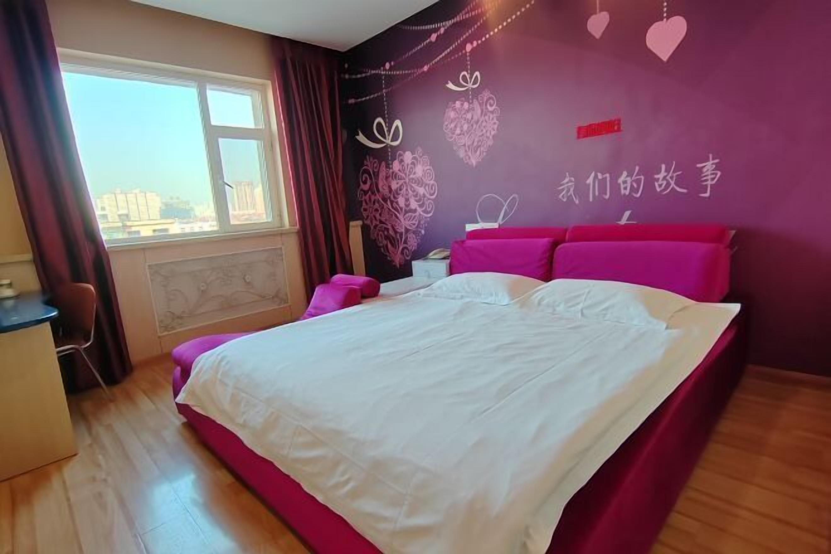 Een slaapkamer met een bed, bureau en raam.