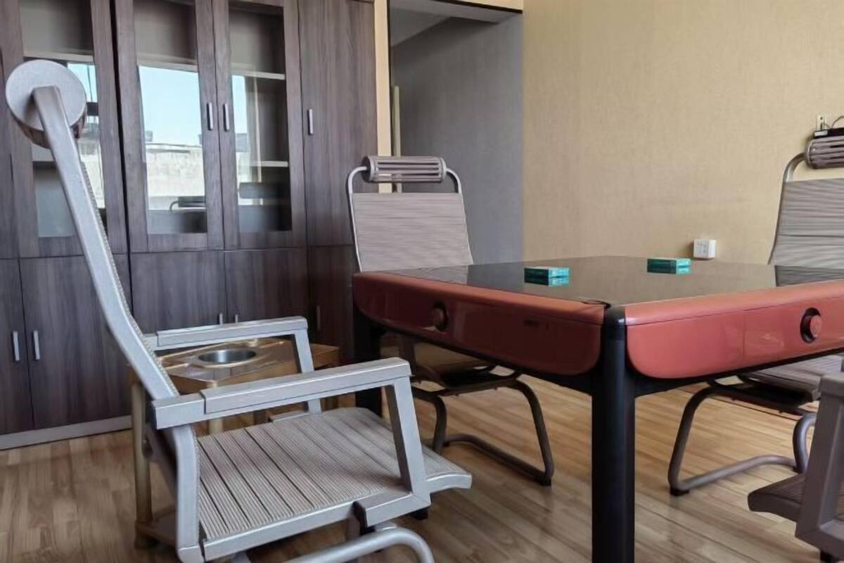 A conference room with a glass table, metal chairs, and a cabinet with glass doors.