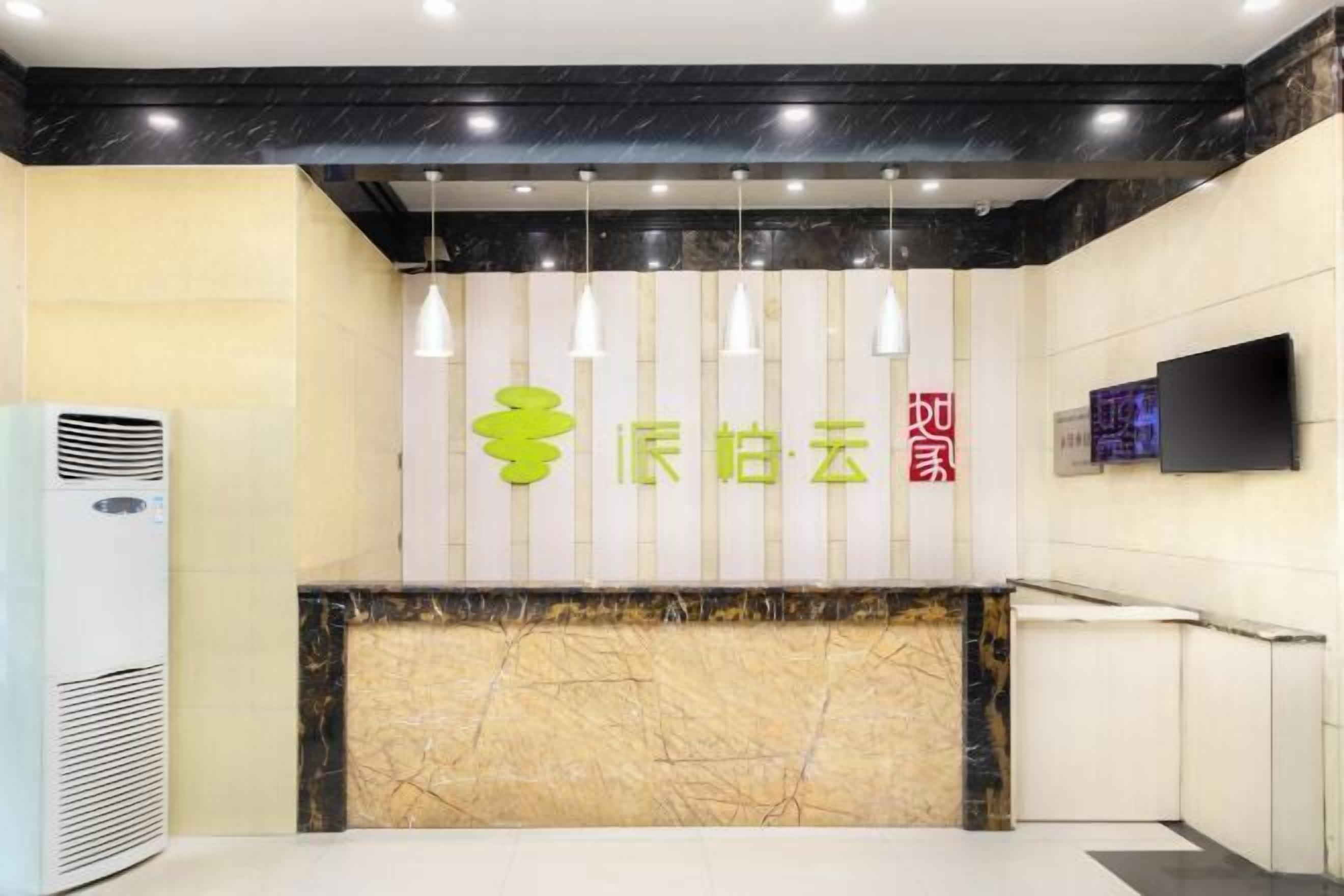 A reception area with a marble counter, air conditioning unit, hanging pendant lights, and a flat-screen TV mounted on the wall.