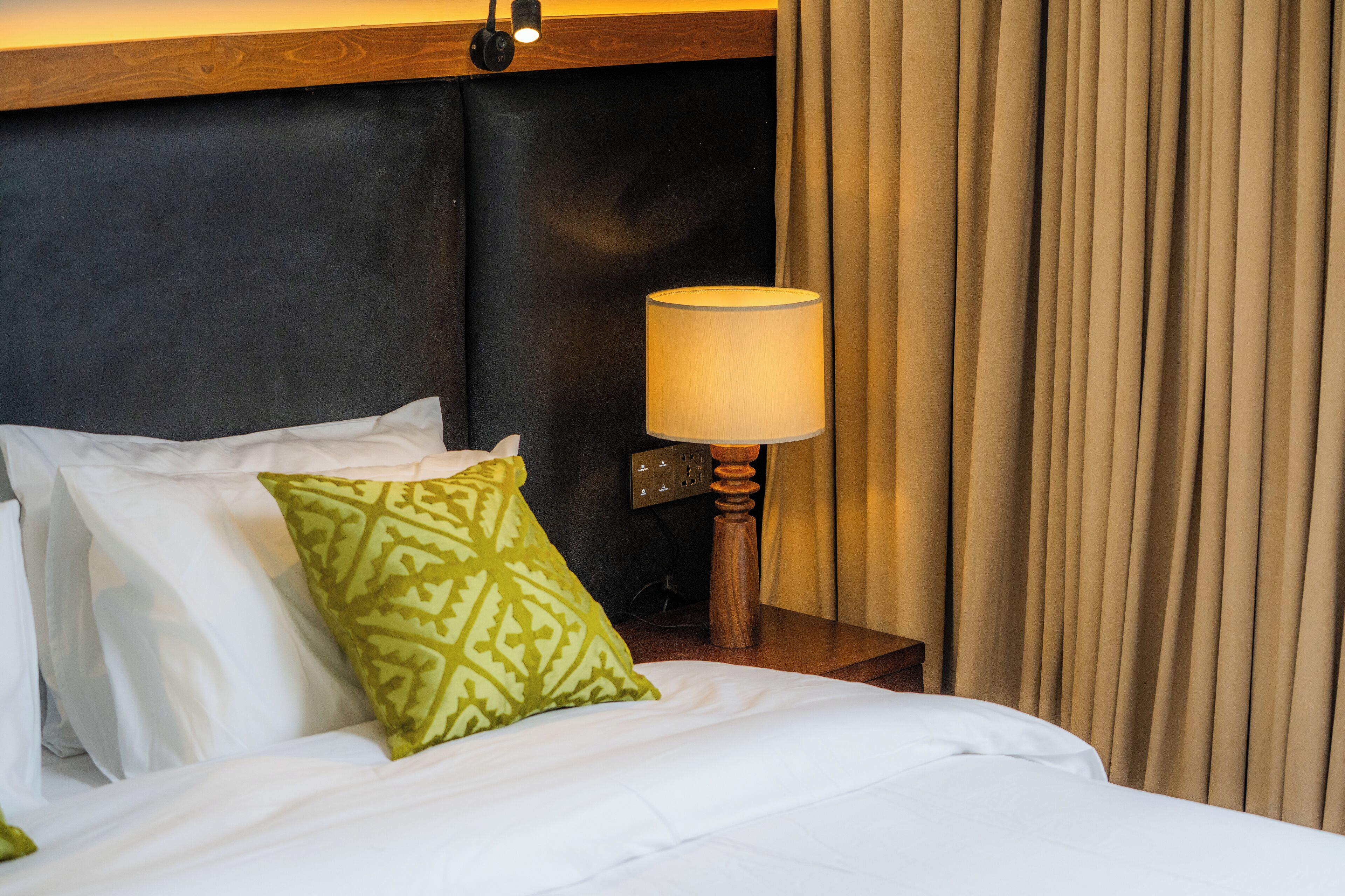 A hotel room with a bed, a lamp, and a curtain.