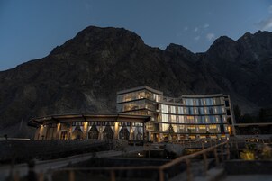 Un hotel moderno con fachada de vidrio, ubicado en una zona montañosa.