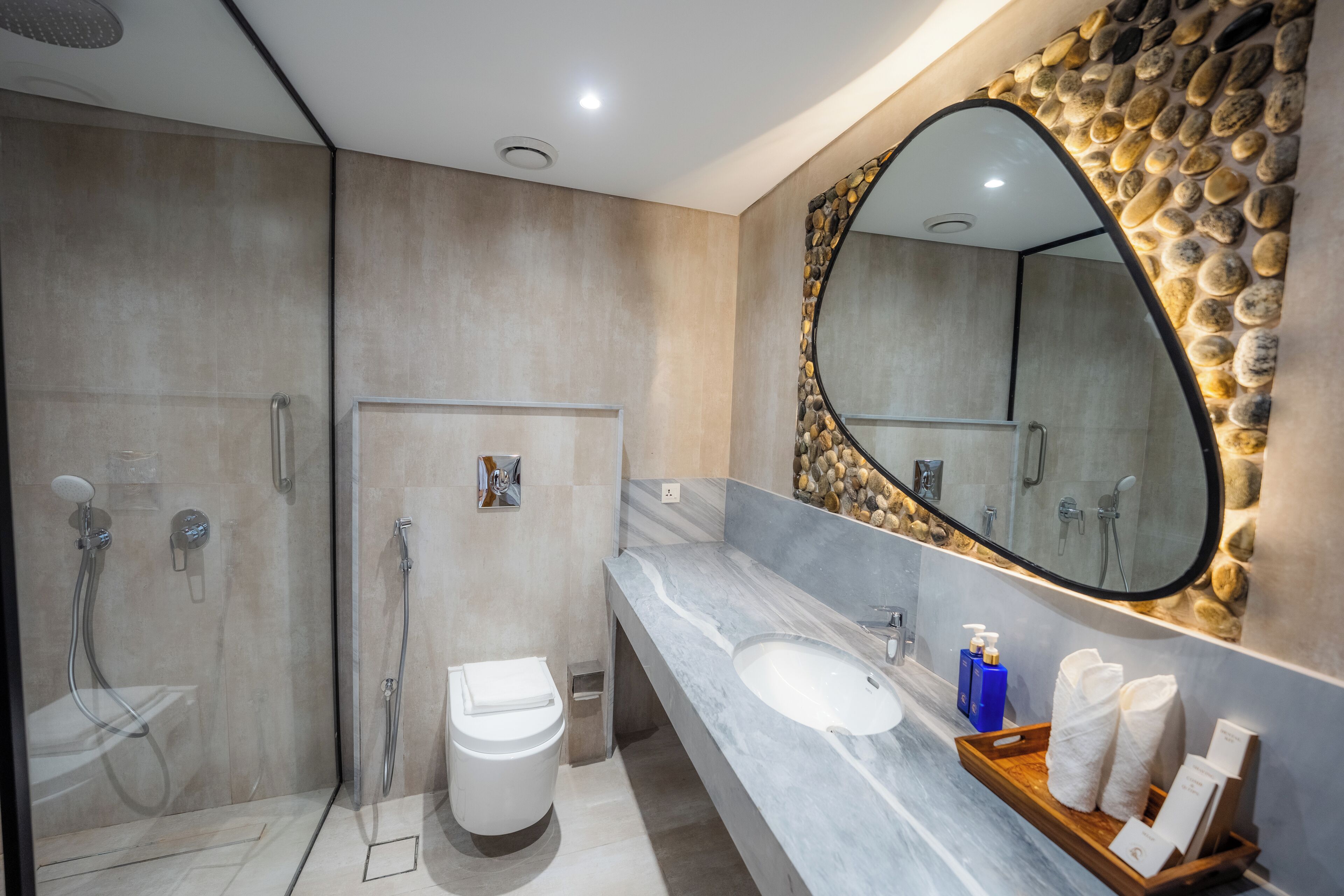 Un baño moderno con lavamanos de mármol, un espejo grande y una zona de ducha.
