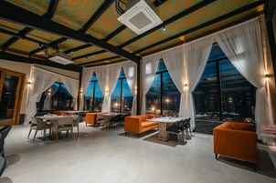Un espacio interior amplio con ventanas grandes, un techo con diseño geométrico y asientos color naranja.