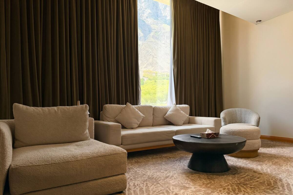 A living room with a sofa, armchair, ottoman, and a coffee table.