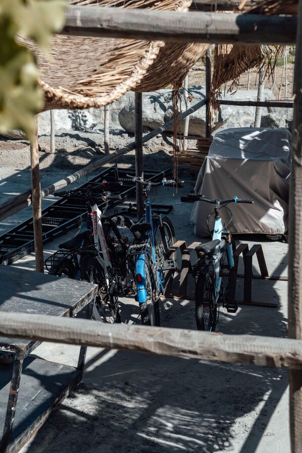A covered bicycle parking area with multiple bicycles and a tent in the background. - FortuNorth (Wazirpur)