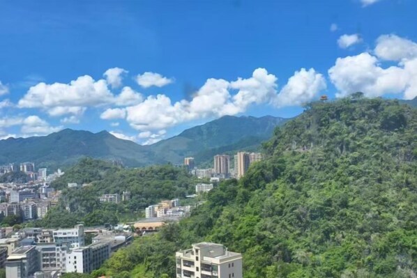 A cityscape with buildings on a hillside, a clear sky, and mountains in the background.