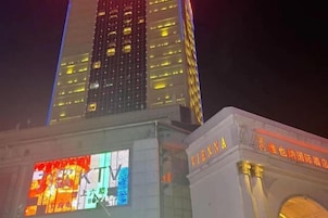 Vista nocturna de un edificio con señalización iluminada y una gran pantalla digital.