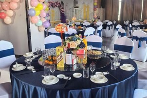 Mesa redonda dispuesta para un evento formal, con platos blancos, vasos y una pieza central.